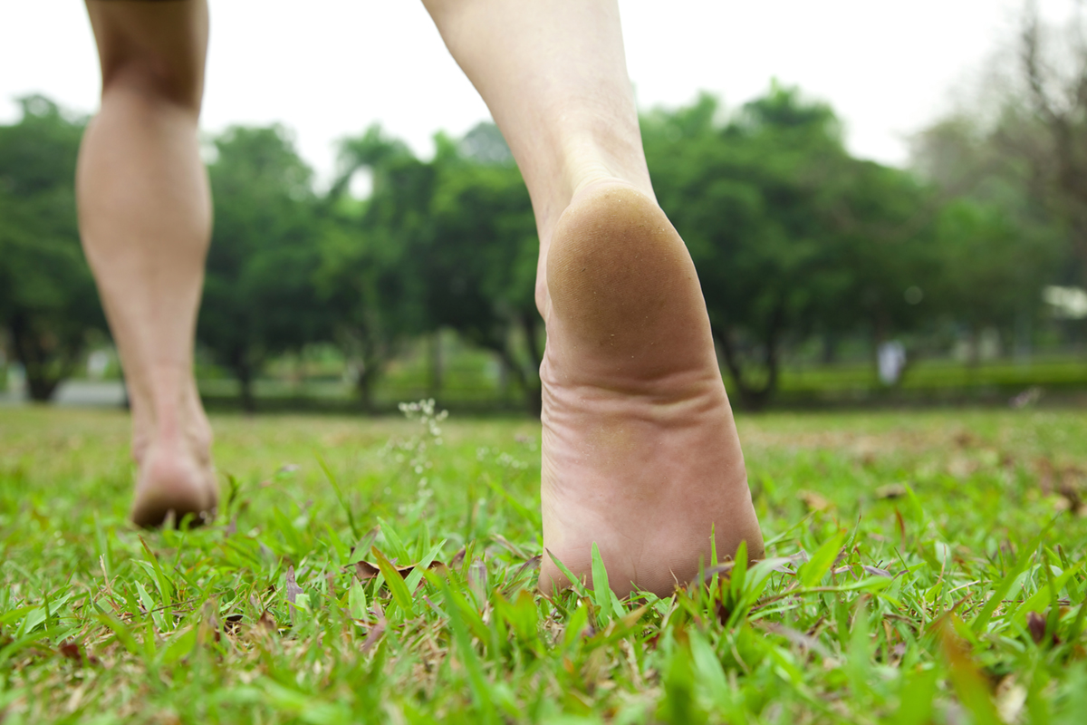 Стучит по земле. Босые ноги мужские. Ступни на траве. Босые мужские ноги на траве. Босыми ногами по траве.